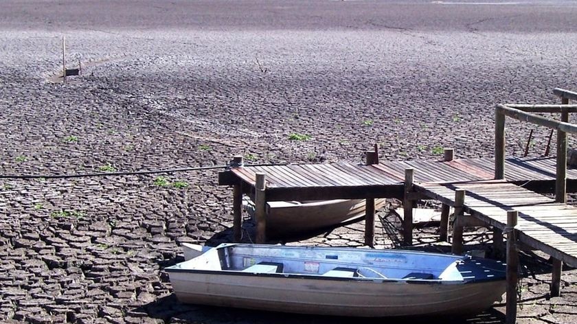 Cracked dry river bed and a jetty with a boat.