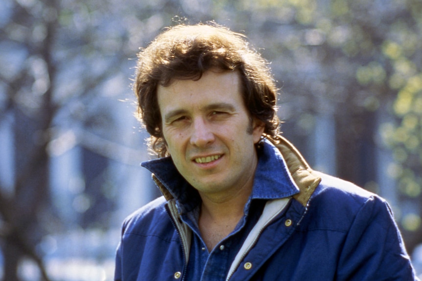 A younger Don McLean with a full head of hair poses for a portrait wearing a blue jacket on a cold sunny day.
