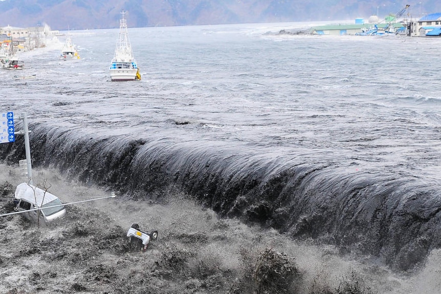 Destructive force... the tsunami wave crashes over a Japanese street