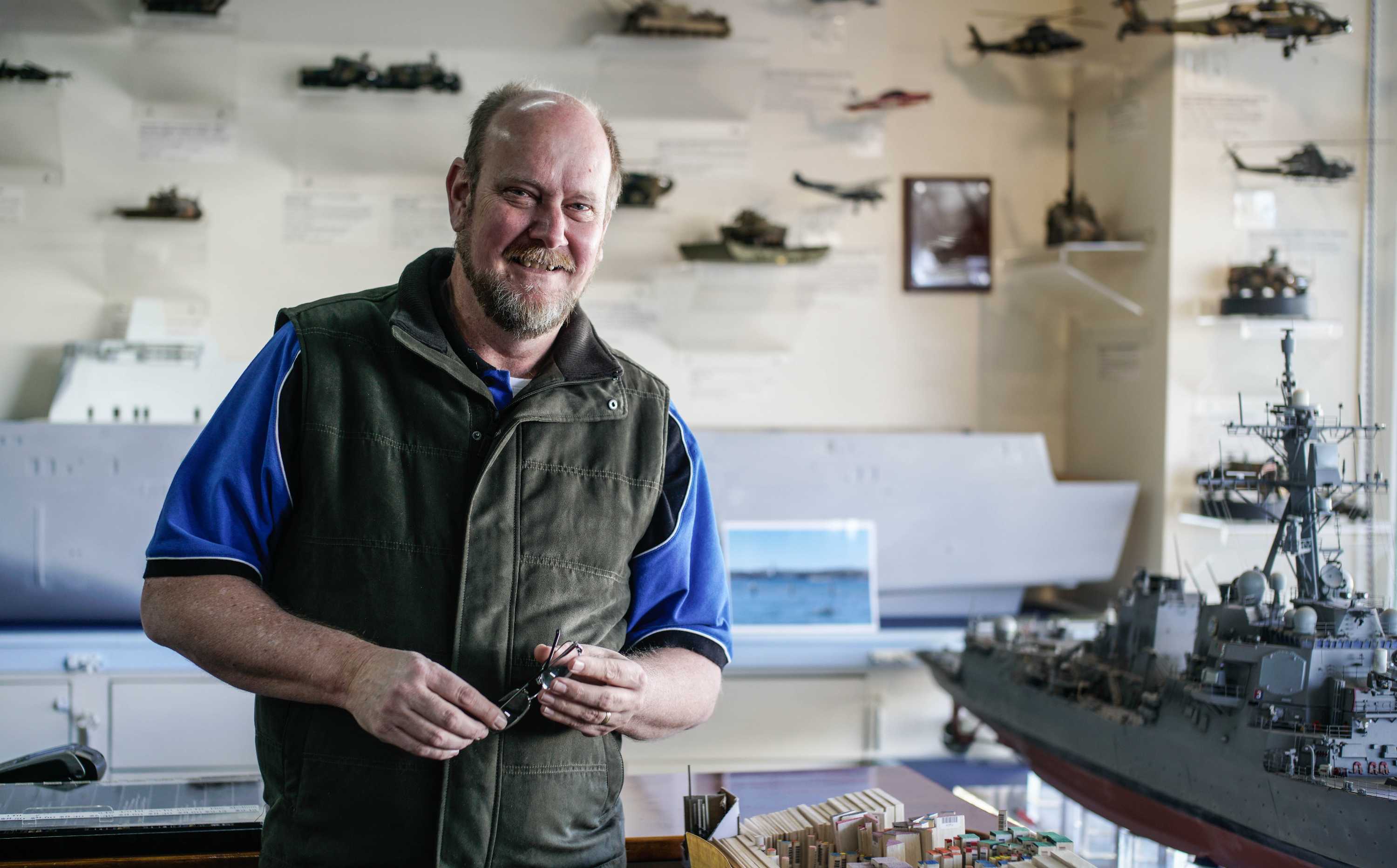 A man standing in front of model ships and vehicles