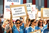 A large rally held outside a hospital with nurses holding signs.