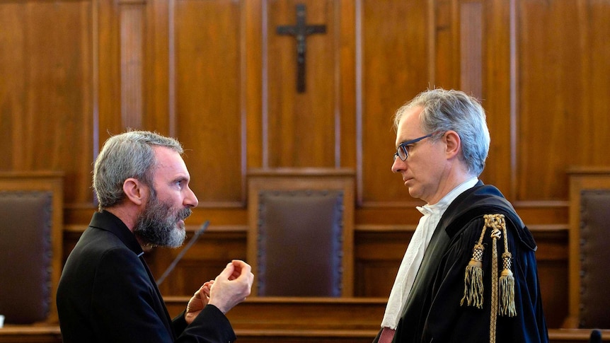Monsignor Carlo Alberto Capella (left) talks to his lawyer Roberto Borgogno inside a Vatican tribunal courtroom during his trial