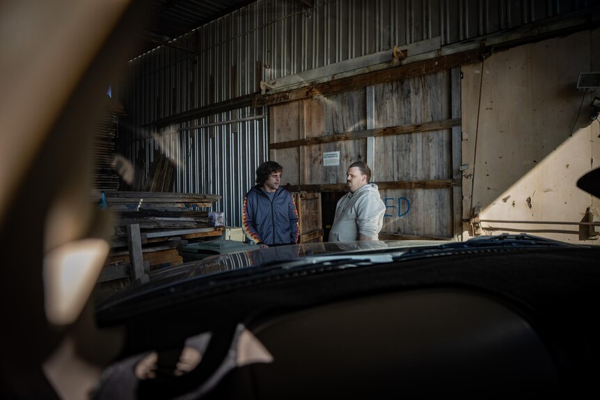 James Paul and Alex Carter inside a gloomy shed.