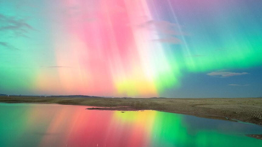 A multicoloured aurora over a lake. 