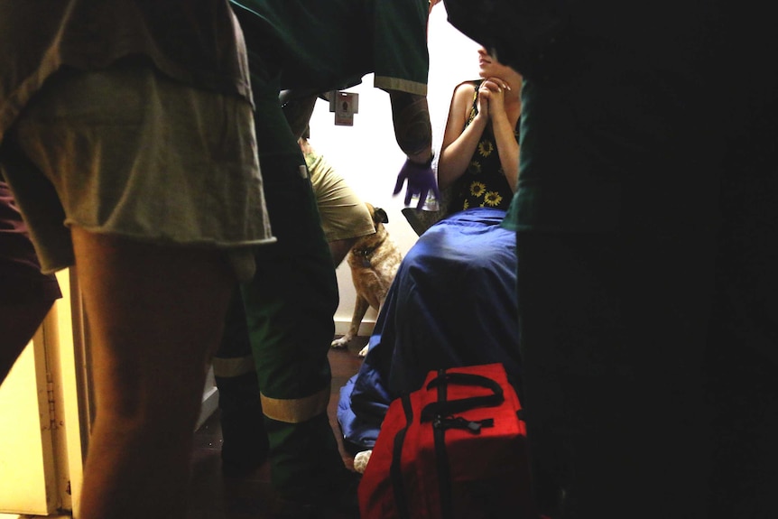Paramedics speak to a patient in a house.