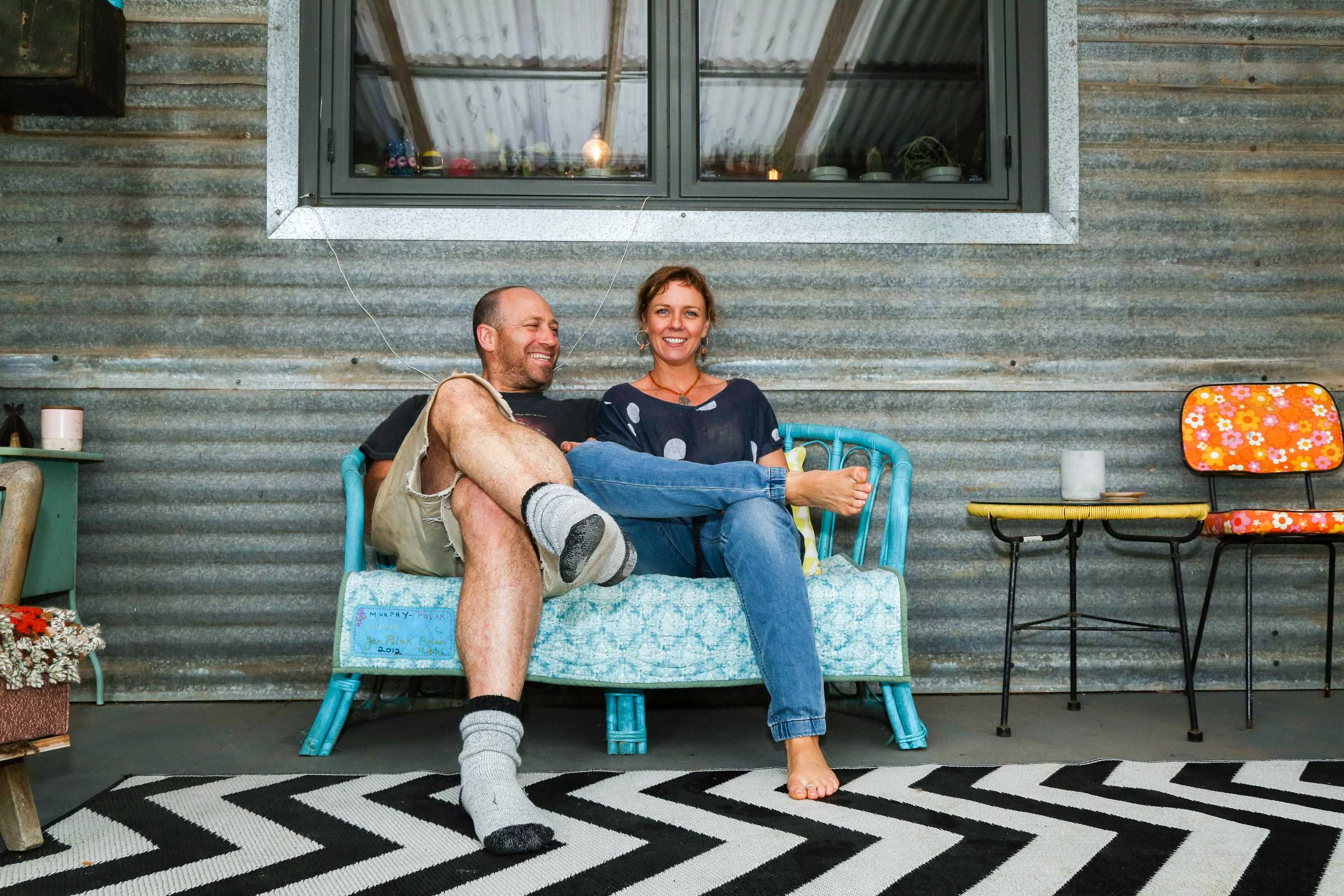 A couple sitting on a bench over a black and white zig zag patterned rug.
