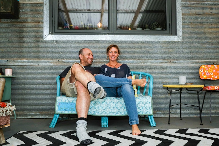 A couple sitting on a bench over a black and white zig zag patterned rug.