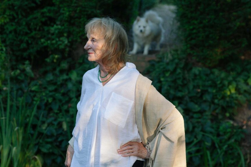 Amanda Feilding stands in her garden with her white dog in the background.