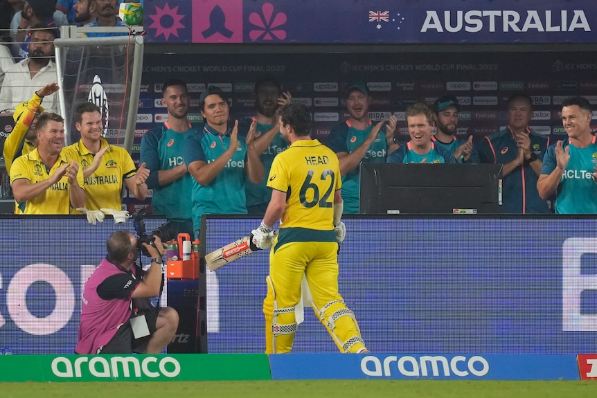 Australian cricketer Travis Head walks off the ground, as his teammates smile and applaud him during a Cricket World Cup final.