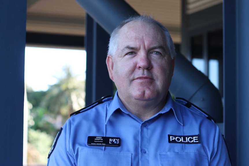 A bald man in police uniform looks at the camera