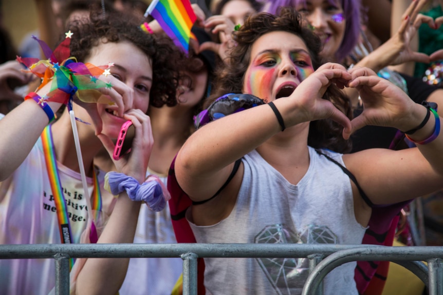 Two woman make heart signs with their hands