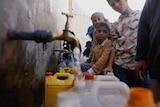 Sanaa residents group around a water tap with gasoline canisters to collect water provided by charities.