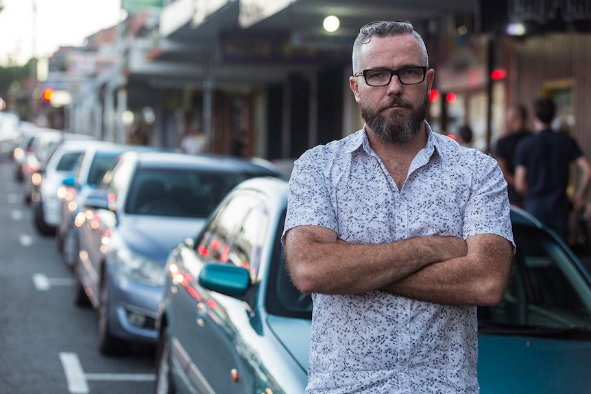 West End Traders Association president Brett Nolan stands with arms crossed in a Brisbane street.