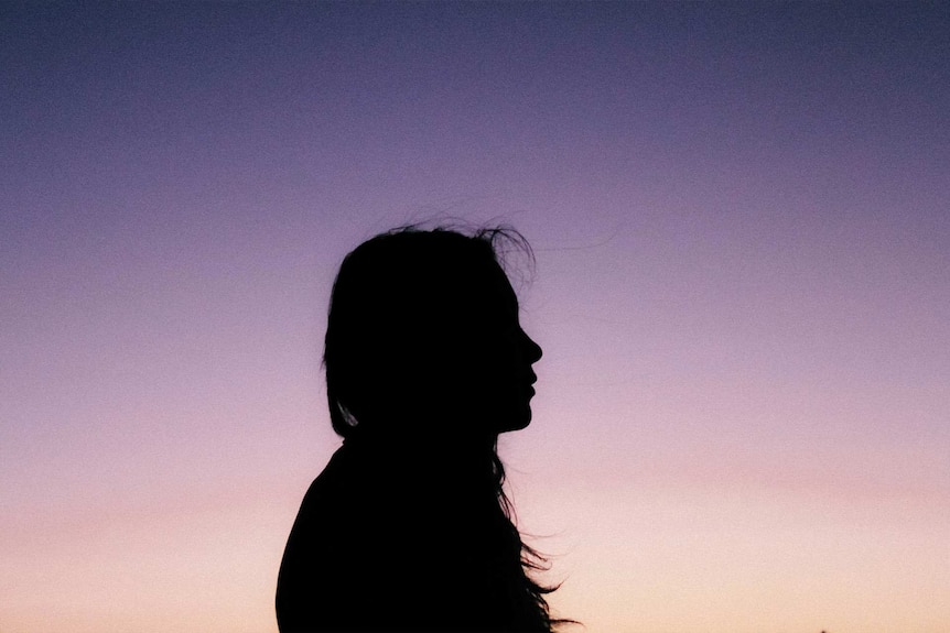 Silhouette of a woman against a purple sunset to depict a story on how to spot domestic violence and what to do.