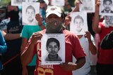 Students from a teacher training college hold pictures of missing students outside building in Chilpancingo