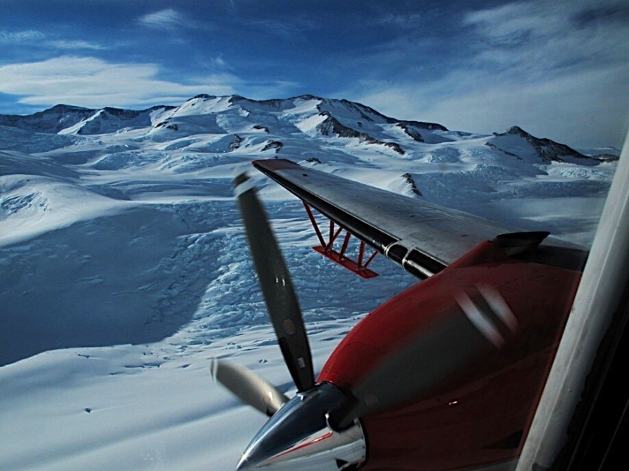 A plane wing extends out over the surface of Antarctica