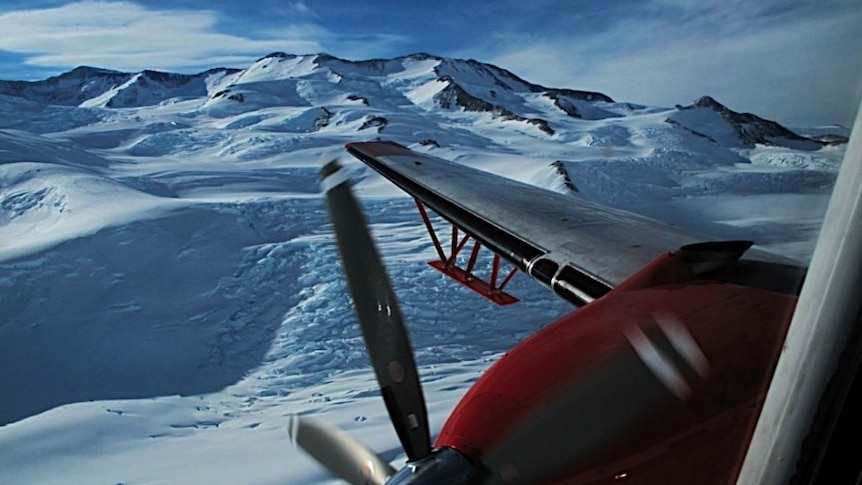 A plane wing extends out over the surface of Antarctica
