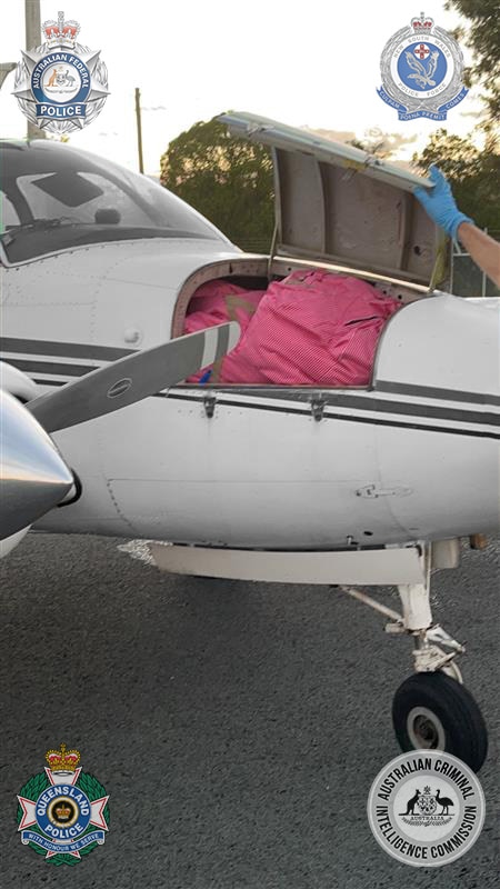 An open compartment at the front of a plane showing pink packages