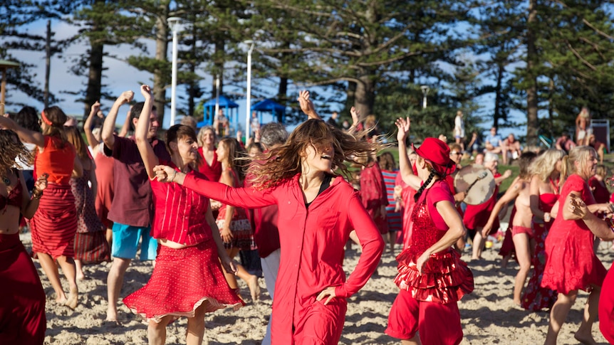Women dressed in red dancing on Byron Bay's Main Beach