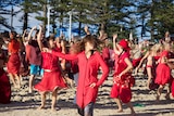 Women dressed in red dancing on Byron Bay's Main Beach