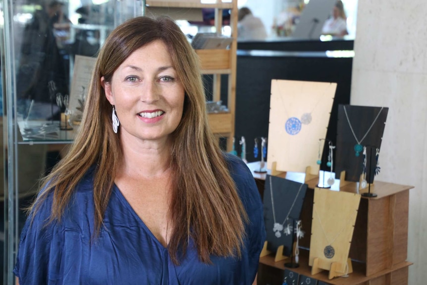 A woman with long brown hair stands in a jewellery shop