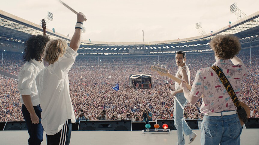 Colour still of Joesph Mazzello, Rami Malek, Gwilym Lee and Ben Hardy as Queen at Live Aid in 2018 film Bohemian Rhapsody.