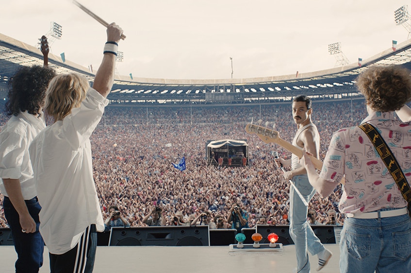 Colour still of Joesph Mazzello, Rami Malek, Gwilym Lee and Ben Hardy as Queen at Live Aid in 2018 film Bohemian Rhapsody.