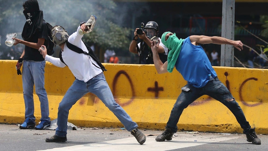 Demonstrators throw stones during a protest in Venezuela