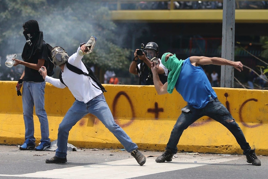 Demonstrators throw stones during a protest in Venezuela