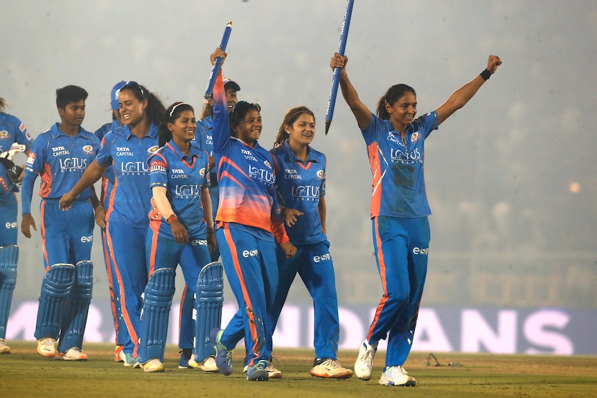 Harmanpreet Kaur holds a stump aloft as she leads her Mumbai Indians off the field after winning the Women's Premier League.