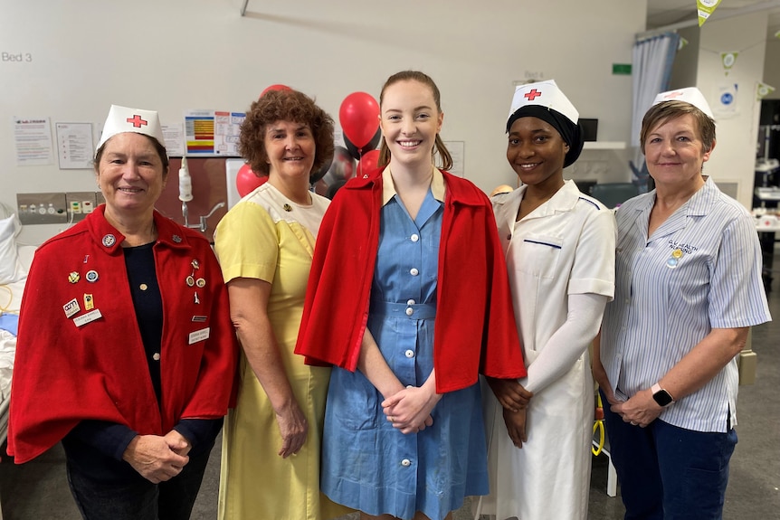 Group of women wear nurse uniforms from different decades.