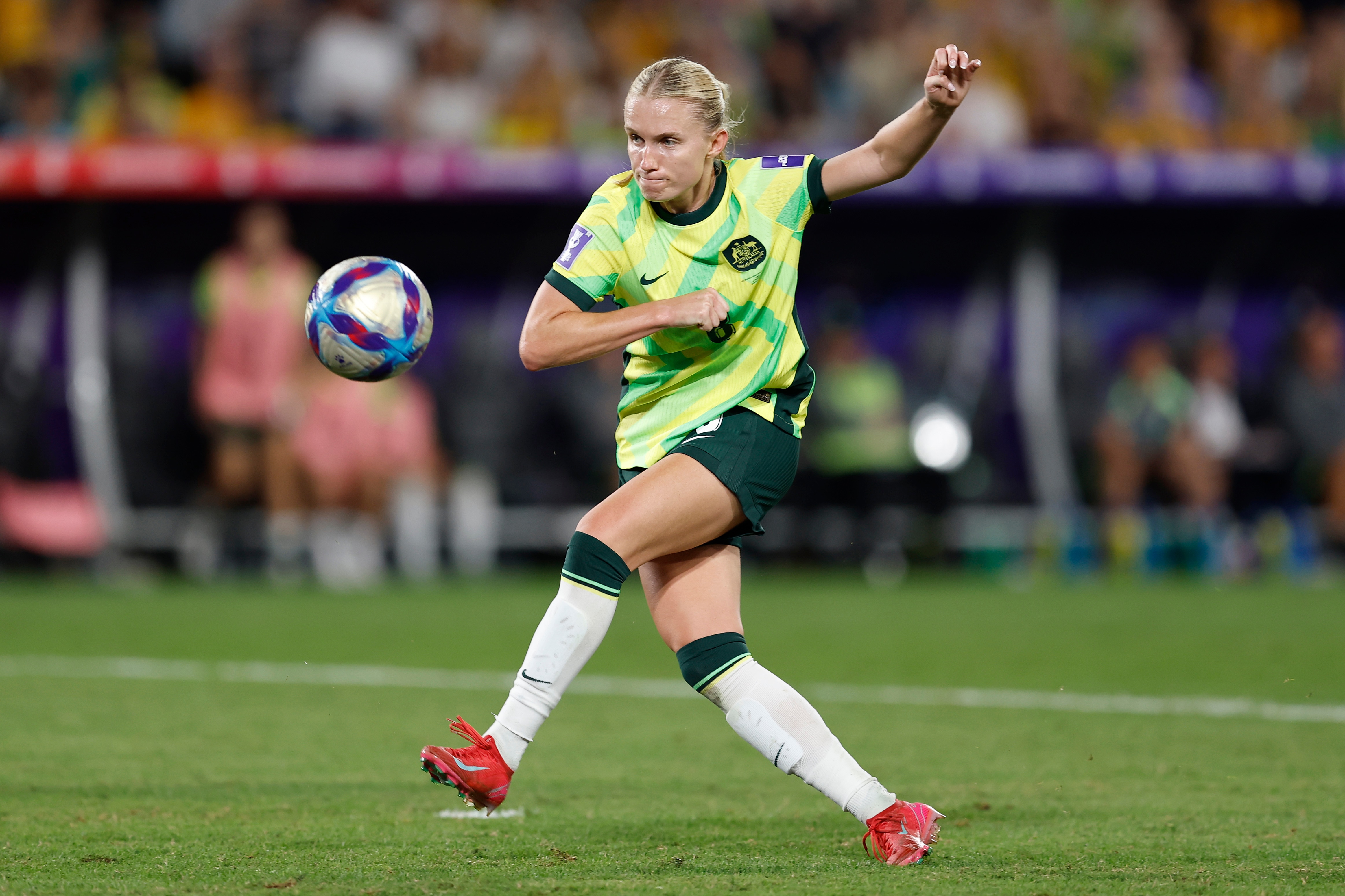 Una jugadora vestida de verde y dorado dispara mientras la pelota se aleja de ella.