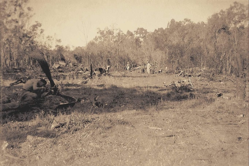 A wide photo of a crash site with people examining wreckage