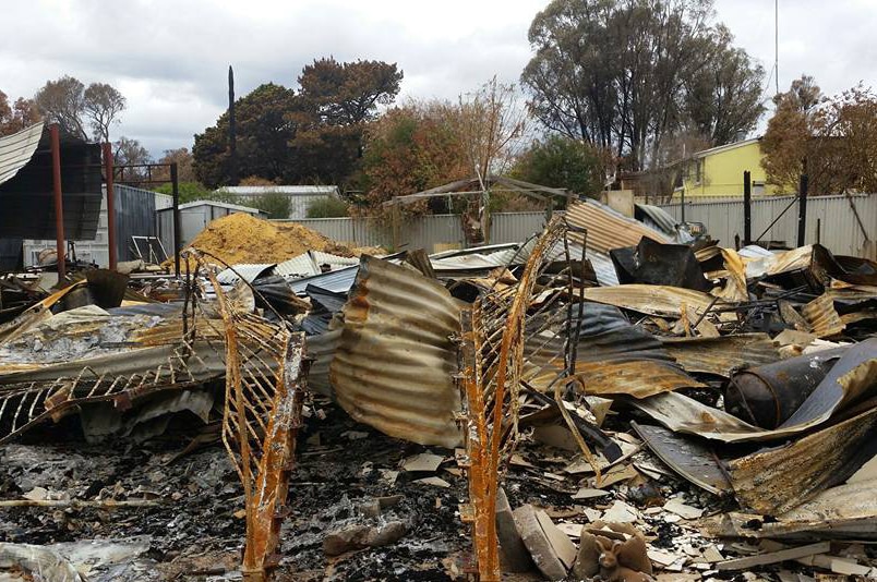 A pile of twisted corrugated iron and other metal, the remains of a fire-devastated house.