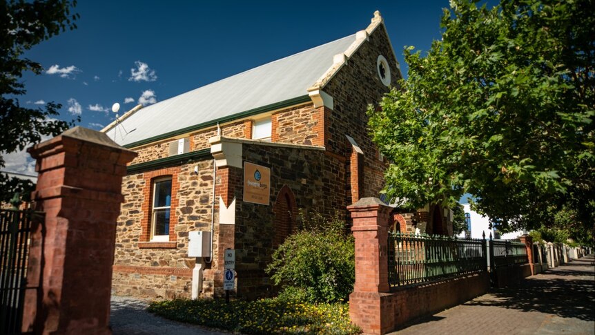 A stately old stone church building with a fence and trees in front of it