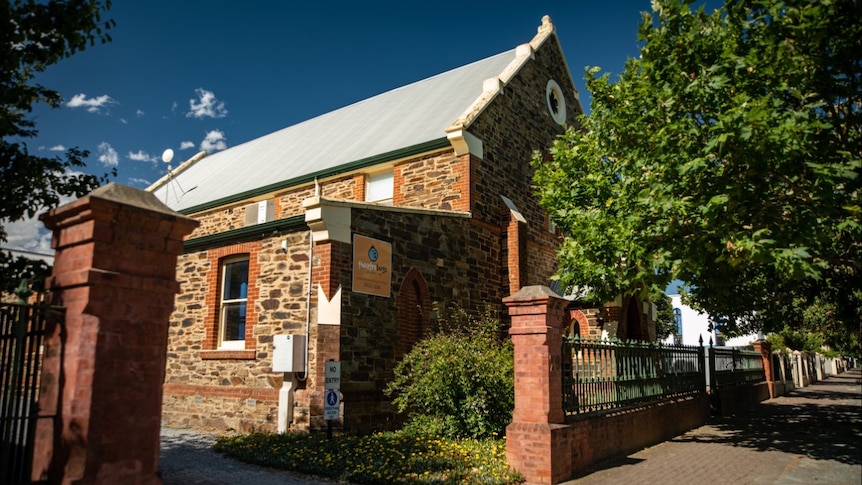 A stately old stone church building with a fence and trees in front of it