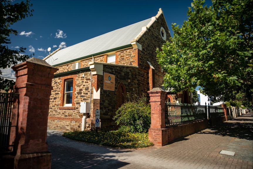 A stately old stone church building with a fence and trees in front of it