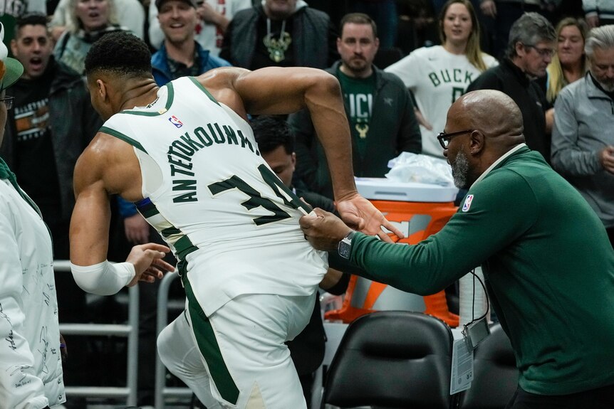 Milwaukee Bucks NBA player Giannis Antetokounmpo is held back by the jersey as he runs up the hallway after a game.