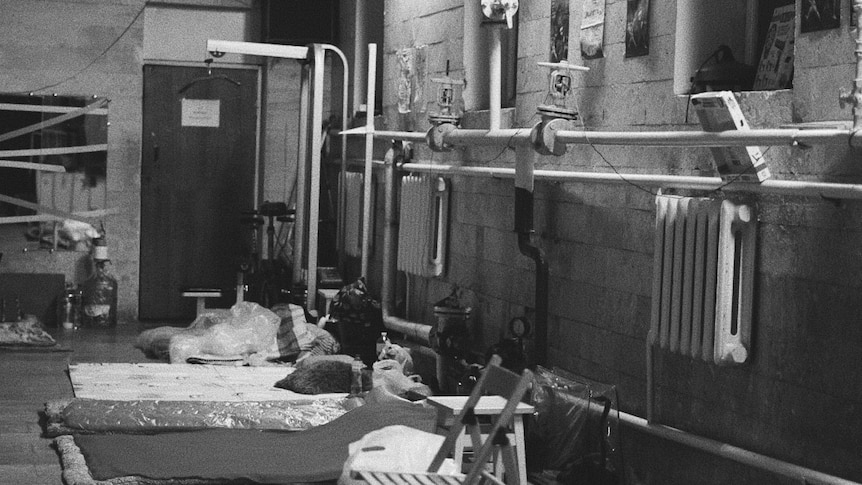 A black and white photo of sleeping mats in a basement