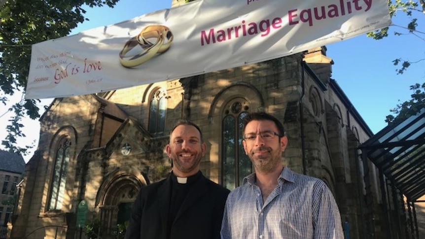 Reverend Ben Gilmour and his partner Scott Miner standing in front of the Paddington Uniting Church.