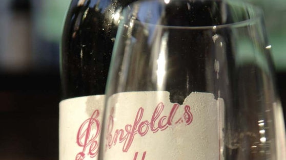 A bottle of Penfolds Grange wine behind an empty glass.