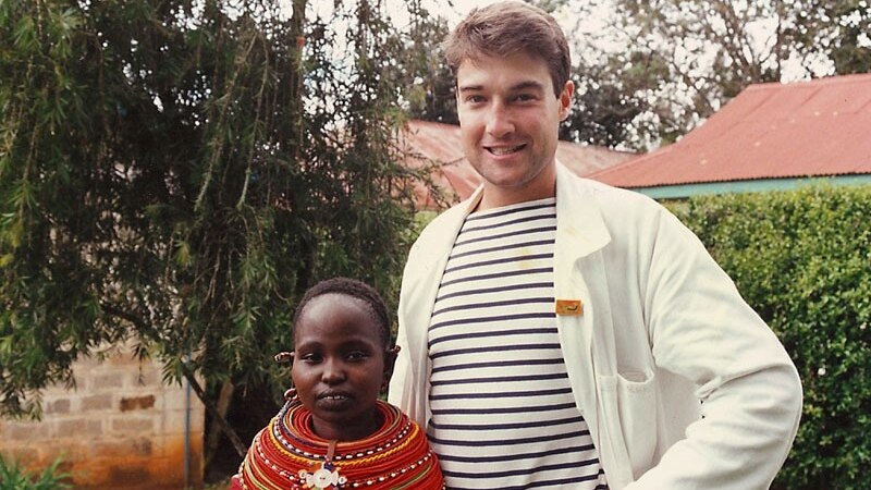 James Muecke, as a young man, standing next to a child in Africa.