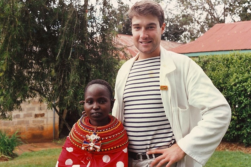 James Muecke, as a young man, standing next to a child in Africa.