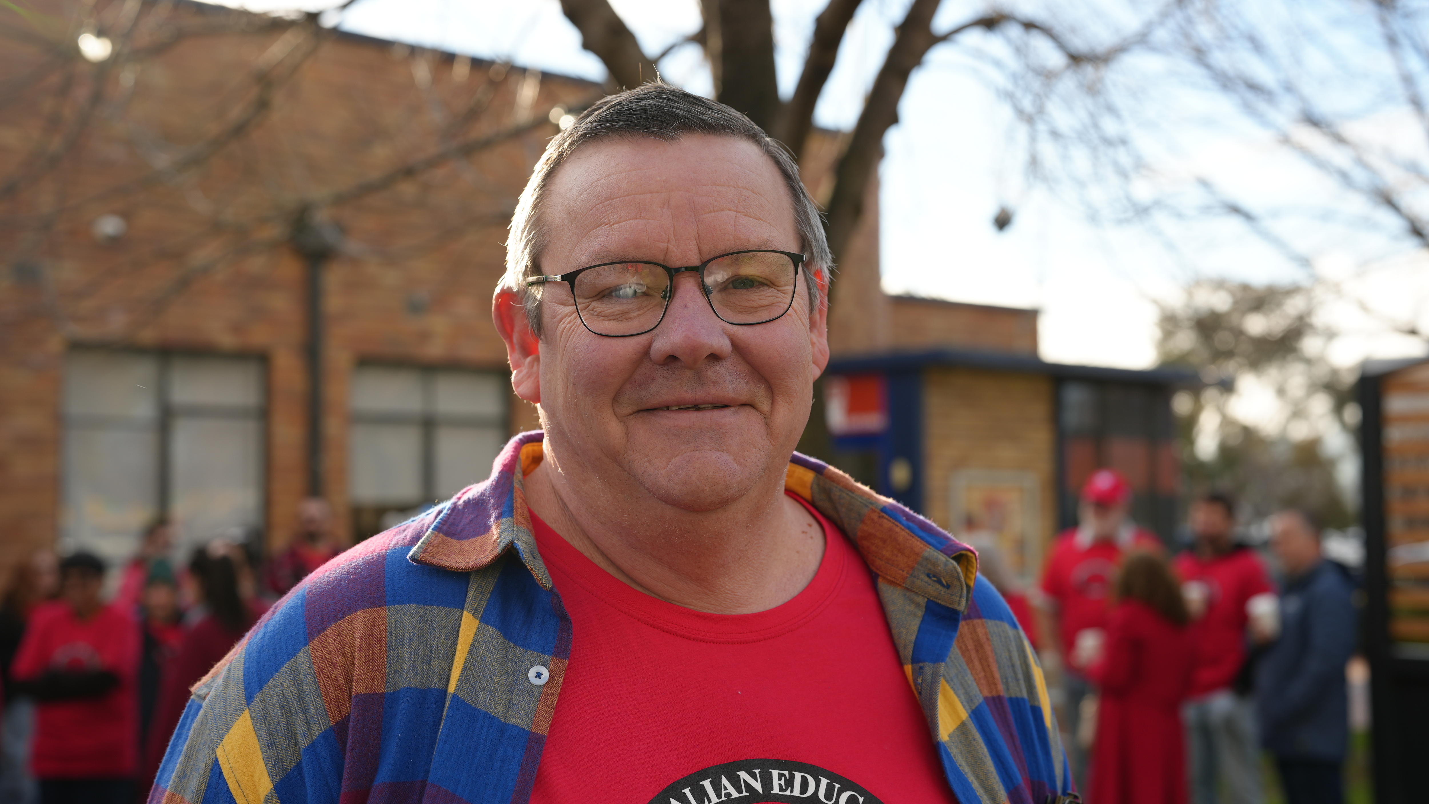 A man in a red shirt and glasses at a protest