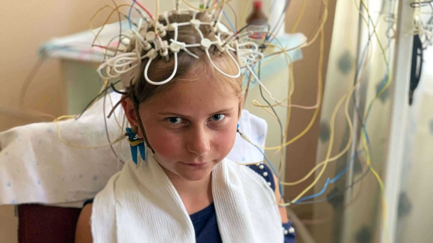 Nine-year-old Kristina sits in a chair patiently as a medical device that's placed on her head conducts radiation tests