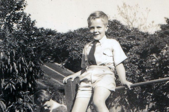 Black and white image of a little boy climbing 