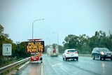 Police enforcing permits sign on border between New South Wales and Victoria. It is raining. 