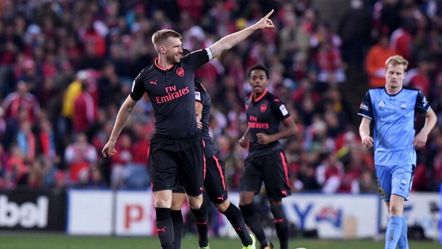 Per Mertesacker points his finger to the crowd with a smile on his face after scoring for Arsenal against Sydney FC