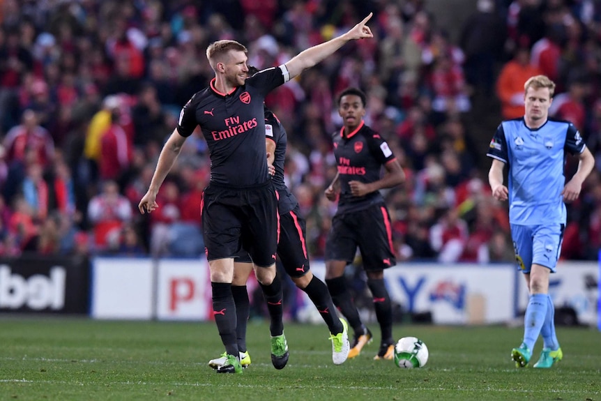 Per Mertesacker points his finger to the crowd with a smile on his face after scoring for Arsenal against Sydney FC