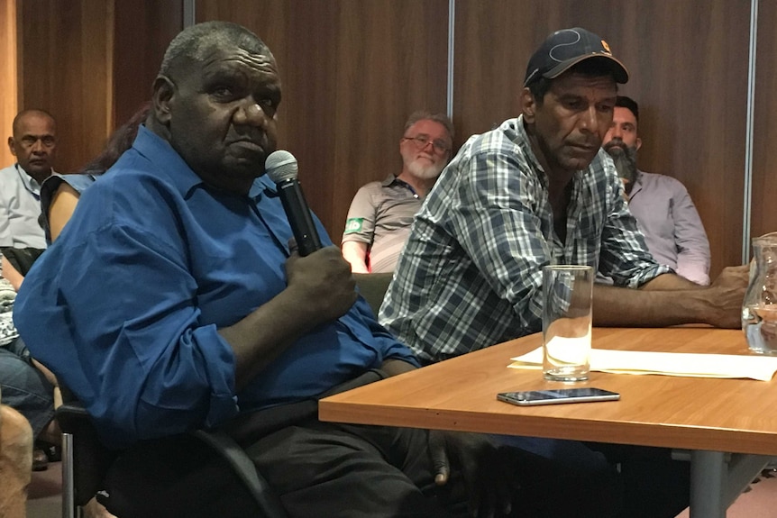 Two Indigenous men sitting at a table in council chambers.